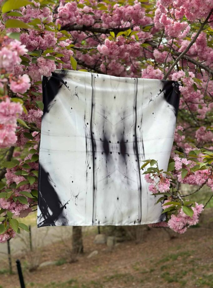 Vibrant pink cherry blossoms with a black and white abstract art piece hanging among the flowers, creating a striking contrast and blending nature with modern artistic expression. Perfect for artistic photography and nature-inspired artwork.