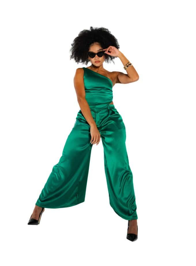 Vibrant green satin jumpsuit with wide-leg pants, stylishly worn by a confident woman, accessorized with black sunglasses and gold bangles, perfect for fashion-forward looks and trendy outfits.