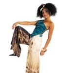 Elegant woman in stylish blue satin top and wide-leg printed pants posing against a white background, showcasing African-inspired fashion and accessories.