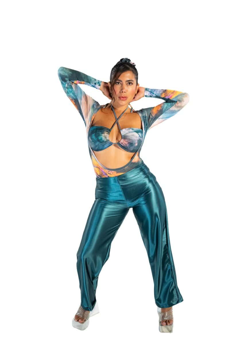 Vibrant colorful fashion model wearing metallic teal pants and a matching cut-out top with a watercolor print, styled in bold, trendy 2023 fashion for a chic and modern look.