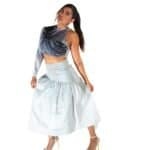 Vibrant woman wearing a black and white printed crop top with a long white skirt, standing confidently against a white background, showcasing unique fashion style.