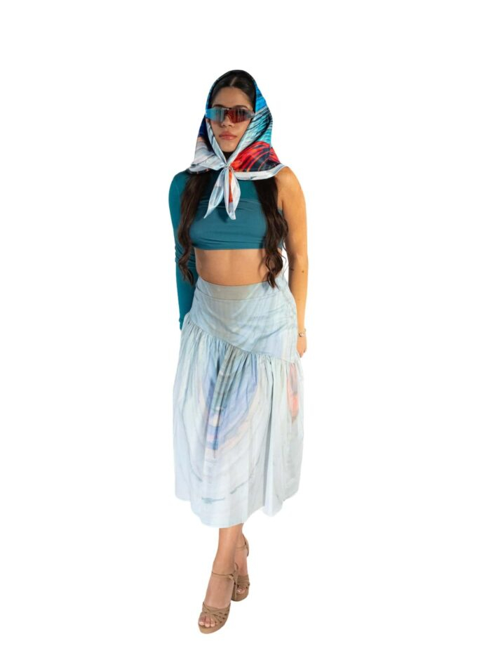 Bold woman in stylish blue crop top, flowing pastel skirt, colorful scarf, and trendy sunglasses, embodying summer fashion and chic accessories.