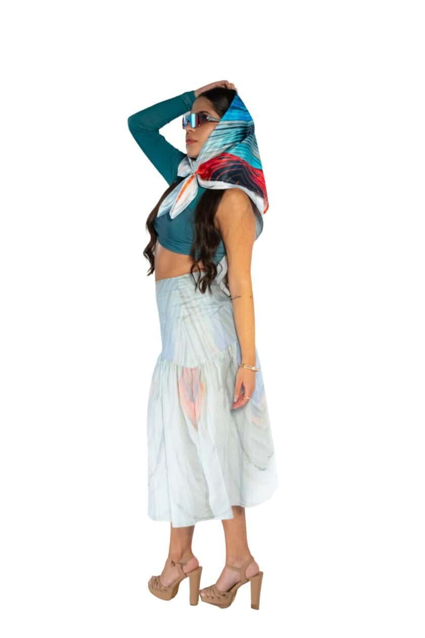 Vibrant fashion-forward woman wearing a colorful silk scarf, stylish crop top, flowing skirt, and high heels, showcasing luxury resort wear and summer style with sunglasses.