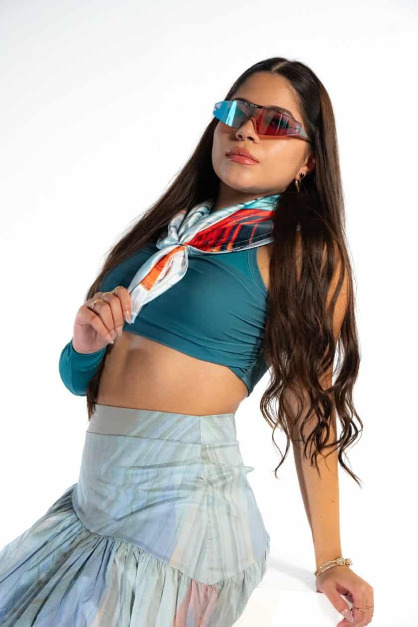 Bright woman in sporty outfit wearing stylish sunglasses and colorful scarf, promoting confiture New York boutique, fashion accessories, and chic casual style.