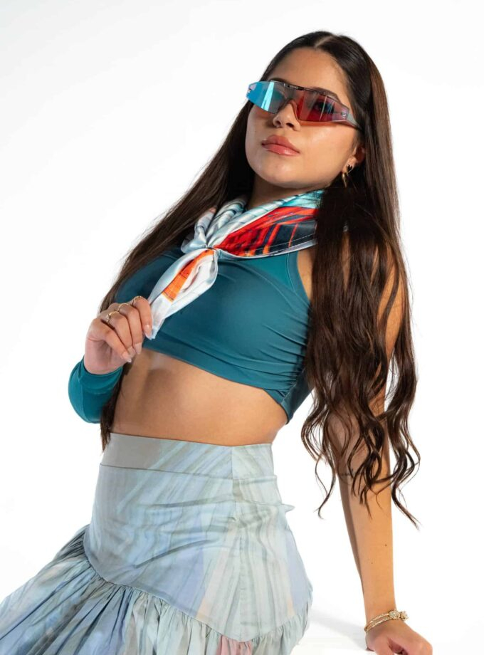 Bright woman in sporty outfit wearing stylish sunglasses and colorful scarf, promoting confiture New York boutique, fashion accessories, and chic casual style.
