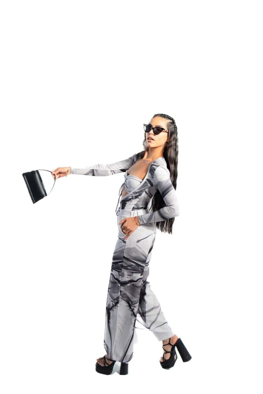 Elegant woman in trendy monochrome outfit holding a black clutch bag, wearing stylish sunglasses and platform heels, showcasing fashion and style for modern urban look.