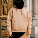 Comfy beige hoodie with a minimalist logo, paired with matching joggers, casual streetwear fashion for men and women, stylish and comfortable for everyday wear.