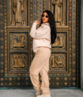 Elegant woman in beige hoodie and sweatpants posing in front of ornate church door, fashion style, urban streetwear, fall outfit, stylish casual attire, NYC fashion scene, trendy and comfortable.